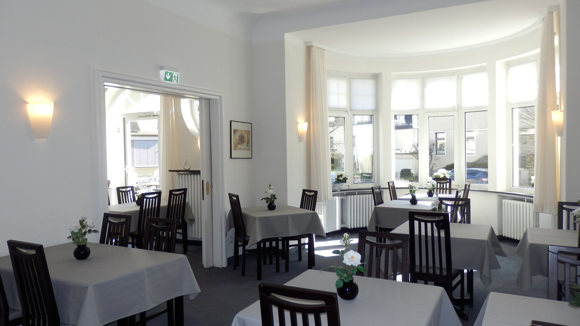 Heller und einladender Frühstücksraum im Hotel Bellevue Hameln mit gedeckten Tischen